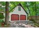 Two car garage features red doors, an upstairs window, and is surrounded by mature trees at 224 Fleming Dr, Durham, NC 27712
