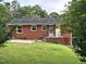 Brick home with a patio and grassy backyard surrounded by lush greenery at 2331 Kennington Rd, Raleigh, NC 27610