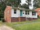 Quaint home with brick foundation and eye-catching teal door, nestled in a green setting at 2331 Kennington Rd, Raleigh, NC 27610