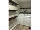 Functional laundry room equipped with washer, dryer, and stylish shelving for storage at 2331 Kennington Rd, Raleigh, NC 27610