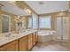 A large mirror and vanity, and a soaking tub with leaded glass windows highlight this relaxing primary bathroom at 2420 Rogerson St, Raleigh, NC 27614