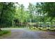 Gated entrance with an American flag; driveway leads towards a pond and trees at 2440 Gardner Holt Rd, Burlington, NC 27215
