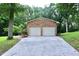 Detached brick garage with two bays and a concrete driveway in a wooded setting at 2440 Gardner Holt Rd, Burlington, NC 27215