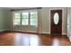 Bright living room featuring hardwood floors, large windows, and a classic front door at 2440 Gardner Holt Rd, Burlington, NC 27215
