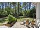 Spacious backyard featuring a stone patio with outdoor dining set, lush lawn, and mature trees at 2704 Farnborough Rd, Raleigh, NC 27613