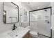 Modern bathroom featuring white tiles, a black-framed shower and a wood vanity at 2704 Farnborough Rd, Raleigh, NC 27613