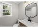 Bright bathroom featuring a marble countertop and a framed octagonal mirror at 2704 Farnborough Rd, Raleigh, NC 27613