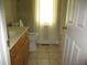 Bathroom with a wooden vanity, tile floor, and a toilet by a bright window with white curtains at 3008 River Hill Ln, Burlington, NC 27217