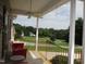 Relaxing front porch featuring a ceiling fan, a cozy red bench, and beautiful views of the yard at 3008 River Hill Ln, Burlington, NC 27217