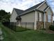 Side yard view with a black metal fence, manicured lawn, and partial stone accents on the home at 3008 River Hill Ln, Burlington, NC 27217