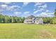 Side view of the white two-story house with a large green yard and trees at 407 Kadir Womble Dr, New Hill, NC 27562