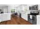 Modern kitchen with white cabinets, stainless appliances, and hardwood floors next to dining area at 4111 Branchwood Dr, Durham, NC 27705