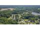 Extensive aerial view features a neighborhood with tree coverage, a lake and bridge, and surrounding wooded areas at 4140 Willow Haven Ct, Raleigh, NC 27616