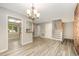 Open dining area with chandelier, wood-look floors, and access to kitchen at 4403 Sunburst Ct, Raleigh, NC 27613