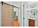 Hallway featuring a modern wooden sliding barn door and a view into a brightly lit office at 508 Bolin Creek Dr, Carrboro, NC 27510