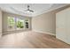 Spacious bedroom with tray ceiling, fan, three large windows, and light hardwood floors at 606 Corrigan Way, Cary, NC 27519