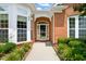 Close-up of the home's entrance featuring a decorative storm door, brick archway, and manicured landscaping at 606 Corrigan Way, Cary, NC 27519
