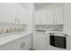 Bright laundry room with white cabinetry, sink, and modern washer and dryer at 606 Corrigan Way, Cary, NC 27519