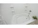 Bright and clean white bathtub and shower combo with tile surround and small potted plant at 617 Woodson Dr, Clayton, NC 27527
