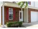 Close-up of the front entrance with brick exterior, red shutters, and well-manicured landscaping at 617 Woodson Dr, Clayton, NC 27527