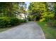 Long driveway leading to a charming yellow home surrounded by lush greenery and mature trees at 6201 King Croydon Ct Ct, Raleigh, NC 27603