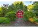 Quaint red outbuilding with white trim surrounded by greenery and a stepping stone path at 6201 King Croydon Ct Ct, Raleigh, NC 27603