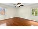Spacious bedroom featuring hardwood floors, a ceiling fan, and natural light from two windows at 6608 Quiet Cove Ct, Raleigh, NC 27612