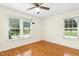 This bedroom features hardwood floors, two windows, and a ceiling fan providing ample light at 6608 Quiet Cove Ct, Raleigh, NC 27612