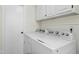 Laundry room with a side-by-side white washer and dryer and storage cabinets at 6608 Quiet Cove Ct, Raleigh, NC 27612