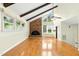 Open living room with a brick fireplace, hardwood floors, beamed ceiling, and multiple windows at 6608 Quiet Cove Ct, Raleigh, NC 27612