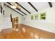 Sunlit living room featuring hardwood floors, beamed ceiling, and a view of the staircase and kitchen at 6608 Quiet Cove Ct, Raleigh, NC 27612