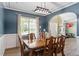 Dining area with navy accent wall, detailed trim, modern light fixture, and wood-look floors at 6901 Rex Rd, Holly Springs, NC 27540