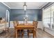 Dining area with navy accent wall, detailed trim, modern light fixture, and wood-look floors at 6901 Rex Rd, Holly Springs, NC 27540