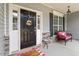 Covered front porch featuring a sitting area, dark front door with sidelights, and stone accents at 6901 Rex Rd, Holly Springs, NC 27540
