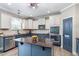 Well-lit kitchen with a central island, stainless steel appliances, and a pantry door at 6901 Rex Rd, Holly Springs, NC 27540