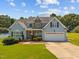Charming two-story home with stone accents, attached garage, and well-manicured lawn under a beautiful sky at 6965 Ogburn Farms Dr, Willow Springs, NC 27592
