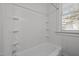 Standard white bathtub with white tiled walls, shower head, and small window at 708 Parker St, Durham, NC 27701
