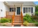 Inviting front porch with brick stairs, wood railings, and lush greenery, creating a warm and welcoming entrance at 741 Rockville Rd, Wake Forest, NC 27587