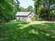 Green backyard with a deck, a white fence, and mature trees surrounding the property at 8504 Carlton Oaks Dr, Wake Forest, NC 27587