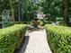 Lush backyard garden featuring stone walkway, fountain, bench, and mature trees at 8504 Carlton Oaks Dr, Wake Forest, NC 27587