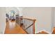 Bright hallway with hardwood floors, wooden railings and a view into the living room at 8851 Mariner Dr, Raleigh, NC 27615