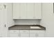 Functional laundry room featuring overhead storage and a sink with white cabinets at 8851 Mariner Dr, Raleigh, NC 27615