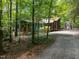 Exterior view of a blue home in a wooded lot, featuring a greenhouse and screened porch at 9709 Greenfield Rd, Chapel Hill, NC 27516