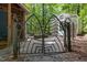 Ornate metal gate leads to a greenhouse and outbuilding, nestled amongst mature trees at 9709 Greenfield Rd, Chapel Hill, NC 27516
