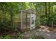 Exterior view of a greenhouse surrounded by nature, providing a dedicated space for gardening and plant cultivation at 9709 Greenfield Rd, Chapel Hill, NC 27516