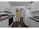 Kitchen with dark wood floors, white cabinets and stainless steel appliances, open to bright living area at 9709 Greenfield Rd, Chapel Hill, NC 27516
