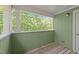 Spacious balcony featuring painted wood floor and white wood-frame openings looking to green trees at 1010 Nicholwood Dr # 301, Raleigh, NC 27605