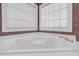 Corner bathtub with white tile and large windows with custom blinds at 105 Bathgate Ln, Cary, NC 27513