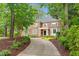 Stately brick home with lush landscaping and a curved driveway nestled among mature trees at 105 Bathgate Ln, Cary, NC 27513