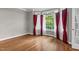 Living room with hardwood floors, bright windows with red curtains, and natural light at 105 Bathgate Ln, Cary, NC 27513